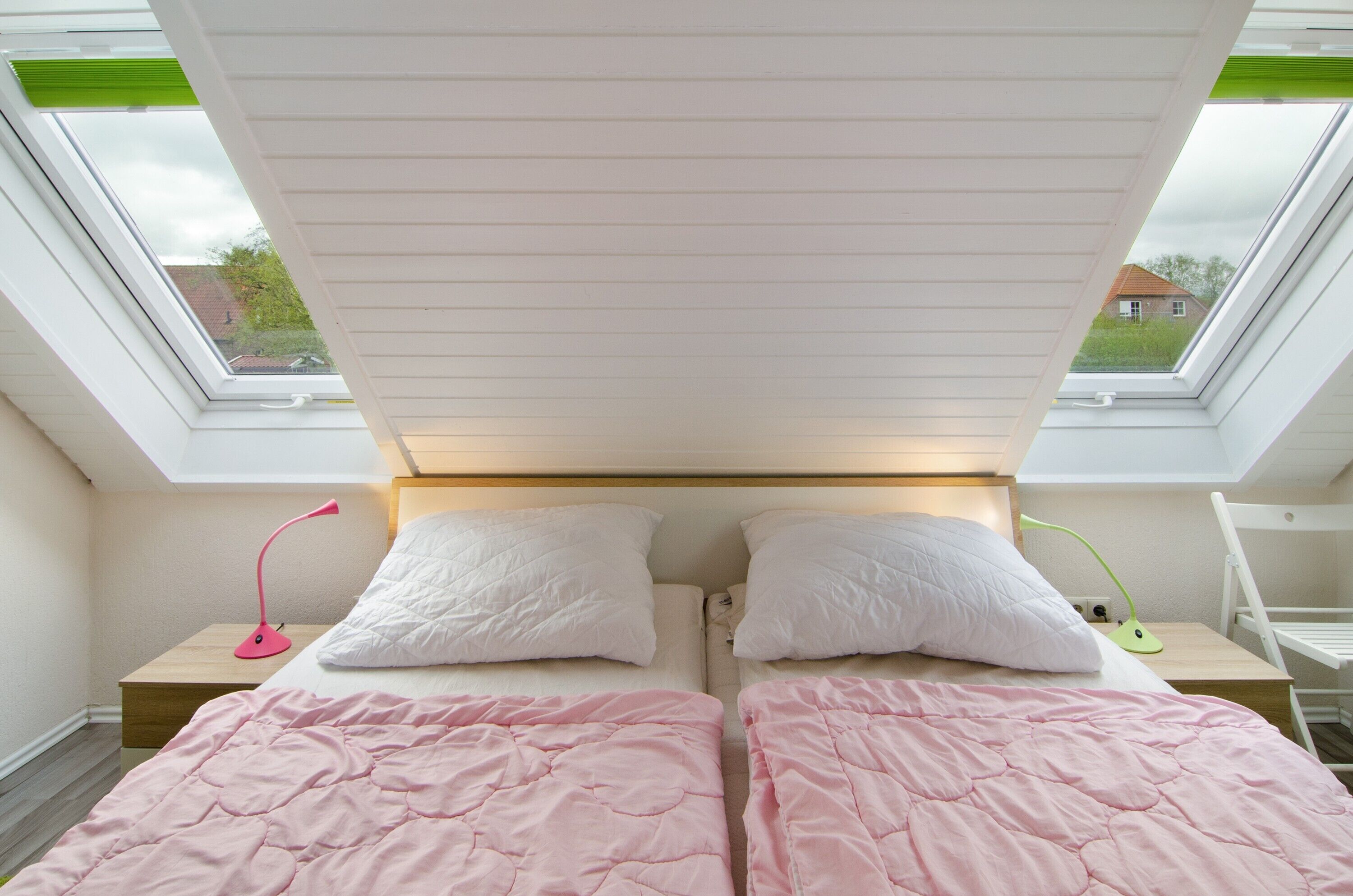 A bedroom with two beds, a skylight, and a view of the outside.