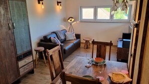A cozy living area with a sofa, wooden dining table, and a window with a view.