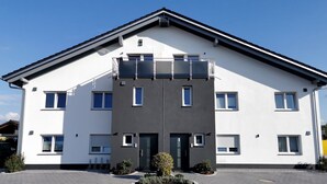Een modern gebouw met een plat dak, veel ramen en een centrale ingang.