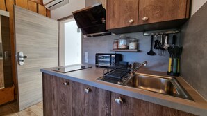 Een kleine keuken met een inbouwtoaster, een spoelbak en houten keukenkastjes.
