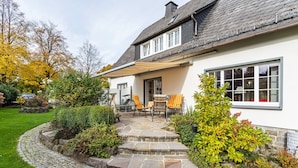 A house with a stone staircase leading to a patio with outdoor furniture.