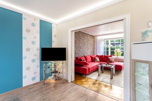 Ein modernes Wohnzimmer mit Fernseher, einem roten Sofa und einem Glastisch.