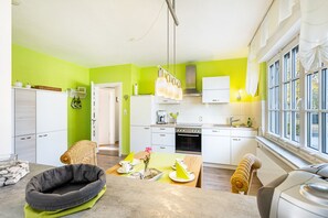 Eine moderne Küche mit weißen Schränken, einem gedeckten Esstisch und einem großen Fenster mit Vorhängen.
