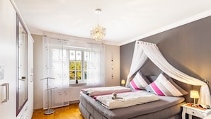 A bedroom with a bed, bedside table, lamp, and a window with curtains.
