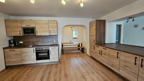A modern kitchen with wooden cabinets, a built-in oven, and a dining area with a bench.