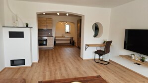 A modern kitchen with wooden cabinets, a built-in oven, and a dining area with a bench.