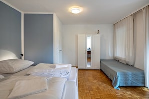 A room with two beds, a wardrobe, a mirror, and a door leading to another room. - Spacious Holiday Home in Northern Hesse with Private Terrace, Garden & Wi-Fi (Homberg (Efze))
