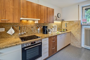 A kitchen with wooden cabinets, a granite countertop, a stove, an oven, and a sink. - Spacious Holiday Home in Northern Hesse with Private Terrace, Garden & Wi-Fi (Homberg (Efze))