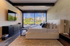 A modern bedroom with a large bed, a desk, a chair, and a view of the city through large windows.