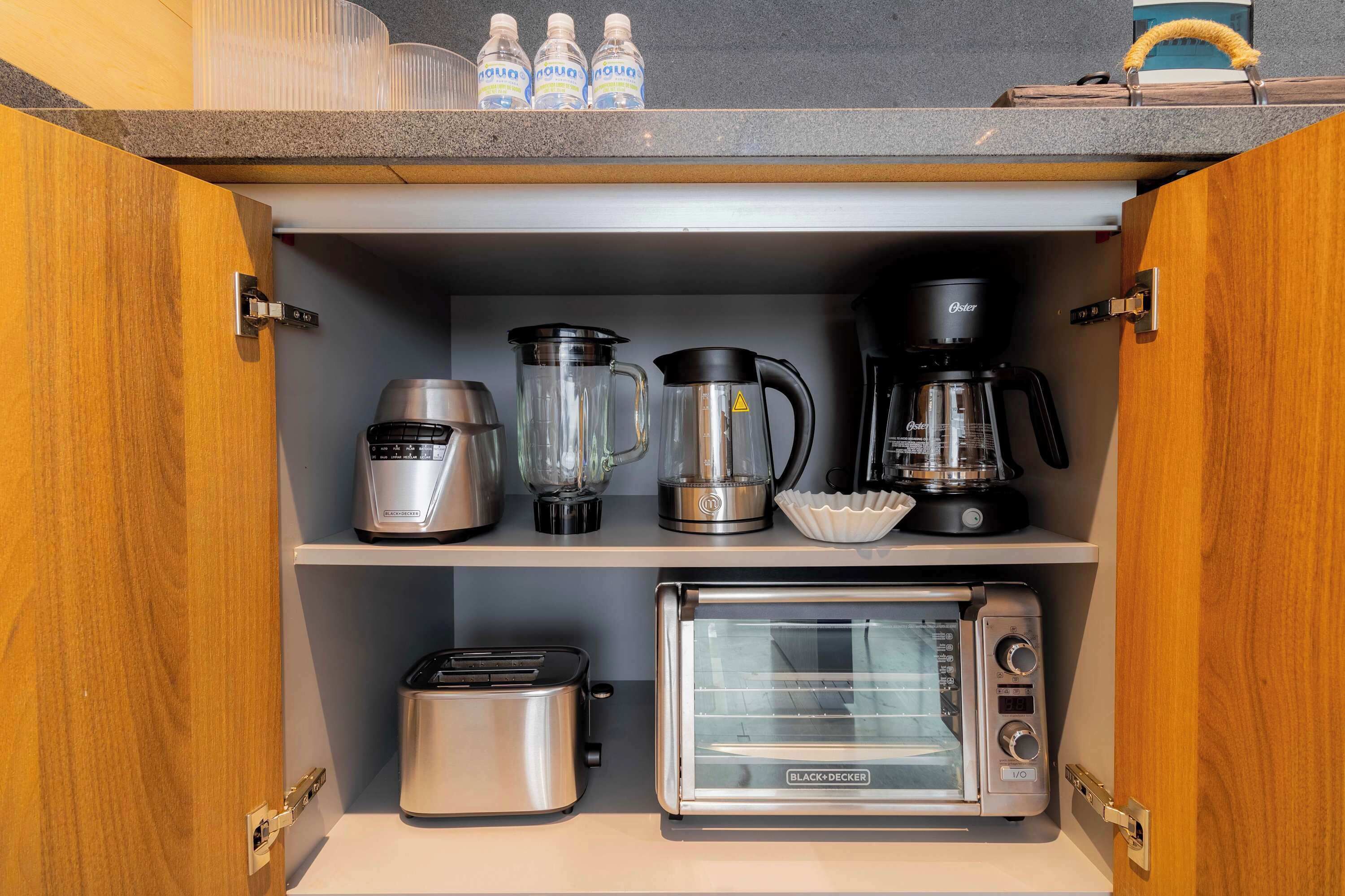 A kitchen with a toaster, coffee maker, blender, and a microwave.