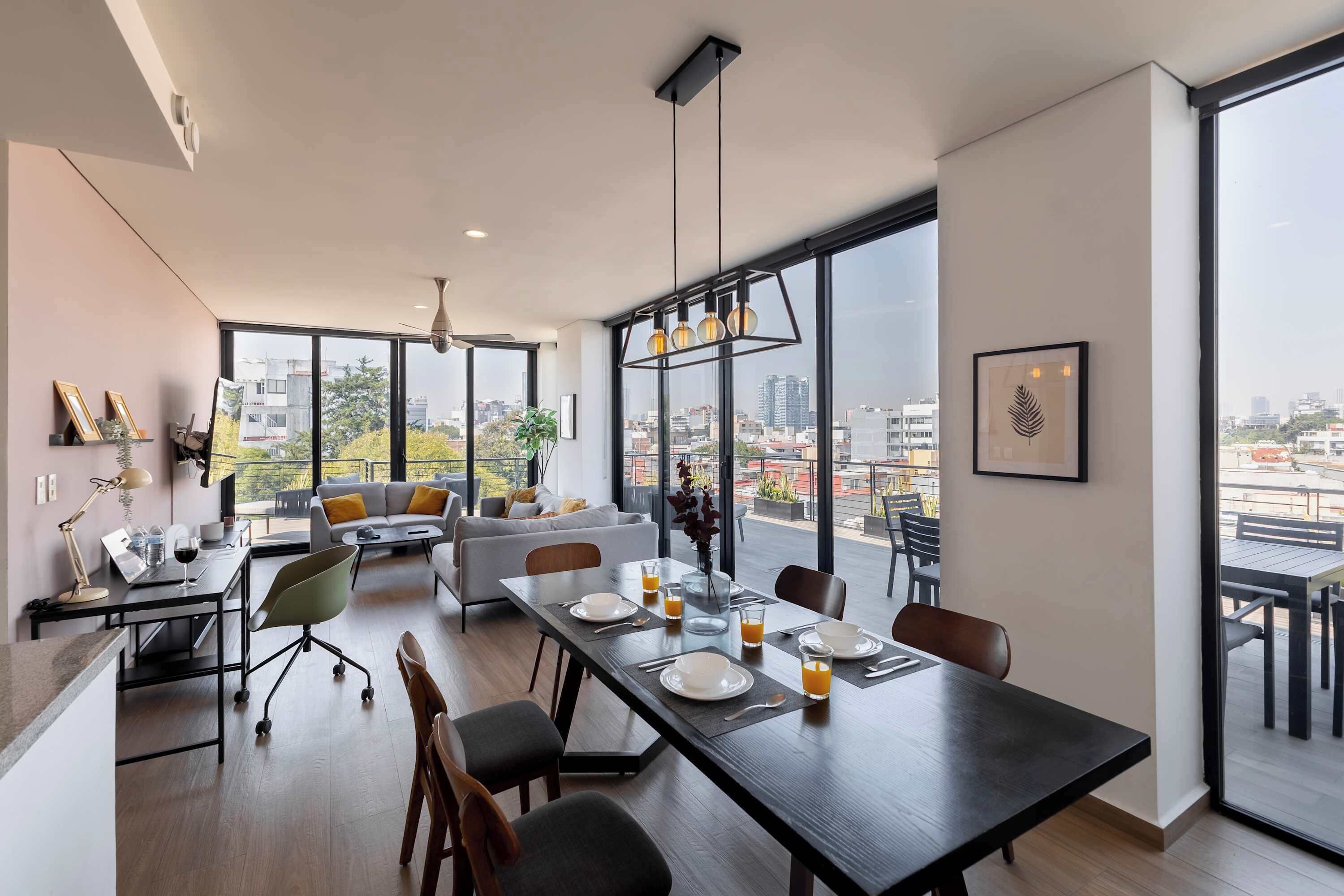 Een moderne woonruimte met een eethoek, een bank en een balkon met uitzicht over de stad.