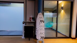 Ein modernes Interieur mit einem Standventilator, einem kleinen Tisch mit einer Pflanze und einer Glastür zum Balkon.