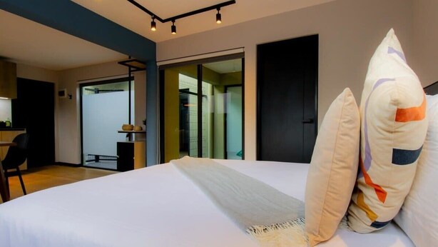 Ein modernes Hotelzimmer mit einem großen Bett, einem Schreibtisch und einer Glastür zum Balkon.