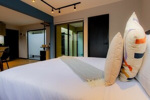 A modern hotel room with a large bed, a desk, and a sliding glass door leading to a balcony. - Capitalia | Chic Loft | Rooftop Garden Inspiration (Ciudad de México)