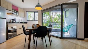 Eine moderne Küche mit Essbereich, großen Fenstern und einer Schiebeglastür zum Balkon.