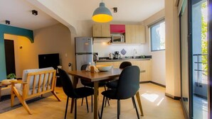 Eine moderne Küche mit Holzschränken, einem Kühlschrank, einer Mikrowelle und einem Essbereich mit Tisch und Stühlen.