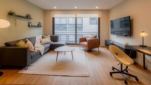 Una sala moderna con sofá, sillón, mesa de centro y un escritorio con silla.