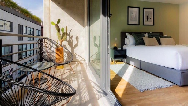 Un dormitorio moderno con una cama, una mesita de noche y un ventanal.