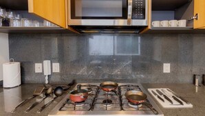 Una cocina equipada con microondas, estufa y diferentes utensilios.