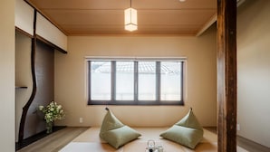 Una habitación japonesa tradicional con suelo de tatami, techo de madera bajo y un ventanal grande.
