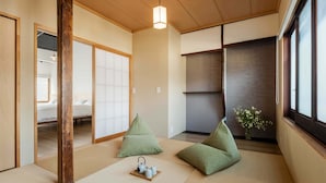 Una habitación japonesa tradicional con suelo de tatami, puerta corredera shoji y vistas a un dormitorio.