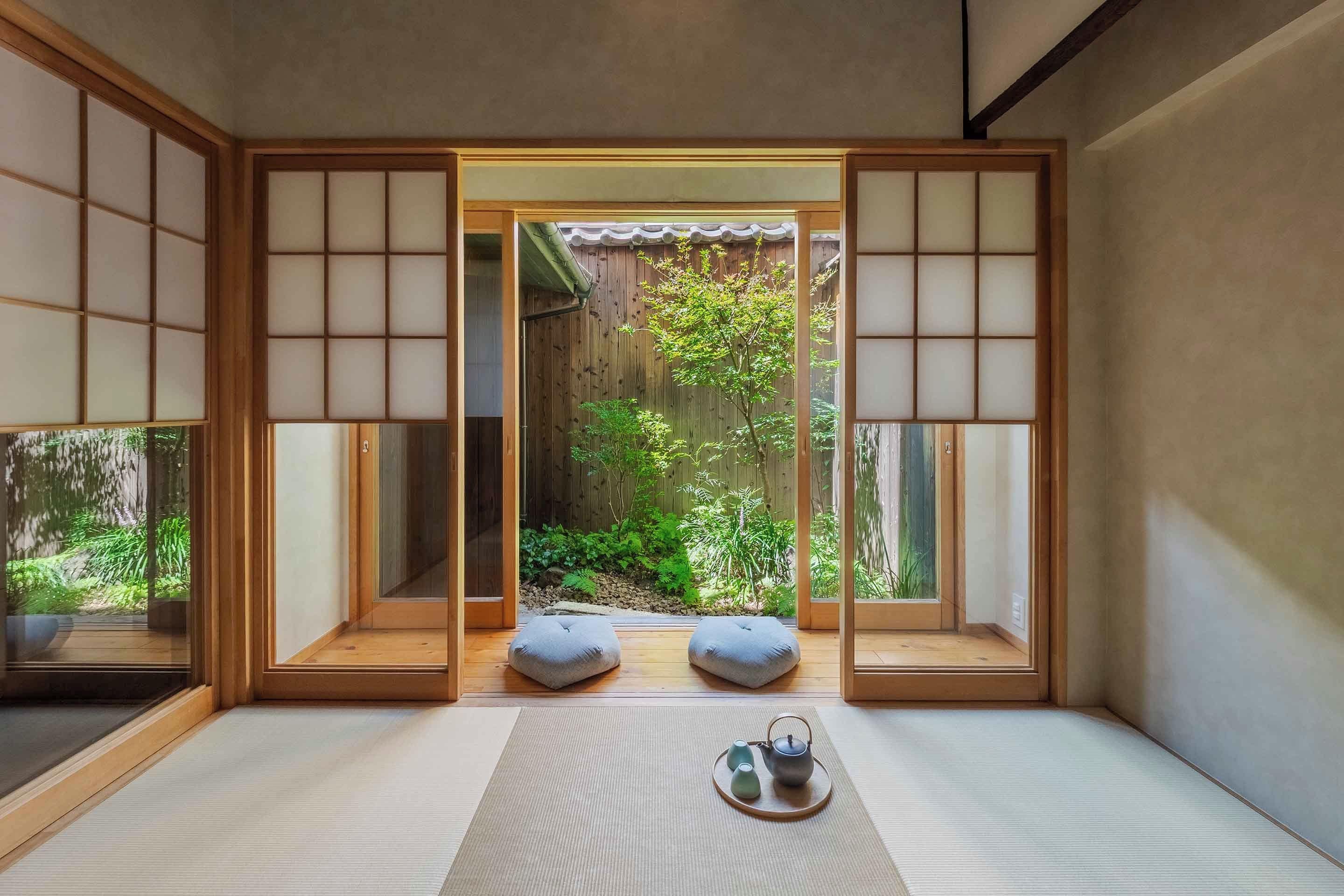 Une pièce de style japonais traditionnel, avec un sol recouvert de tatamis, une porte coulissante en papier de riz (shoji) et une vue sur un jardin.