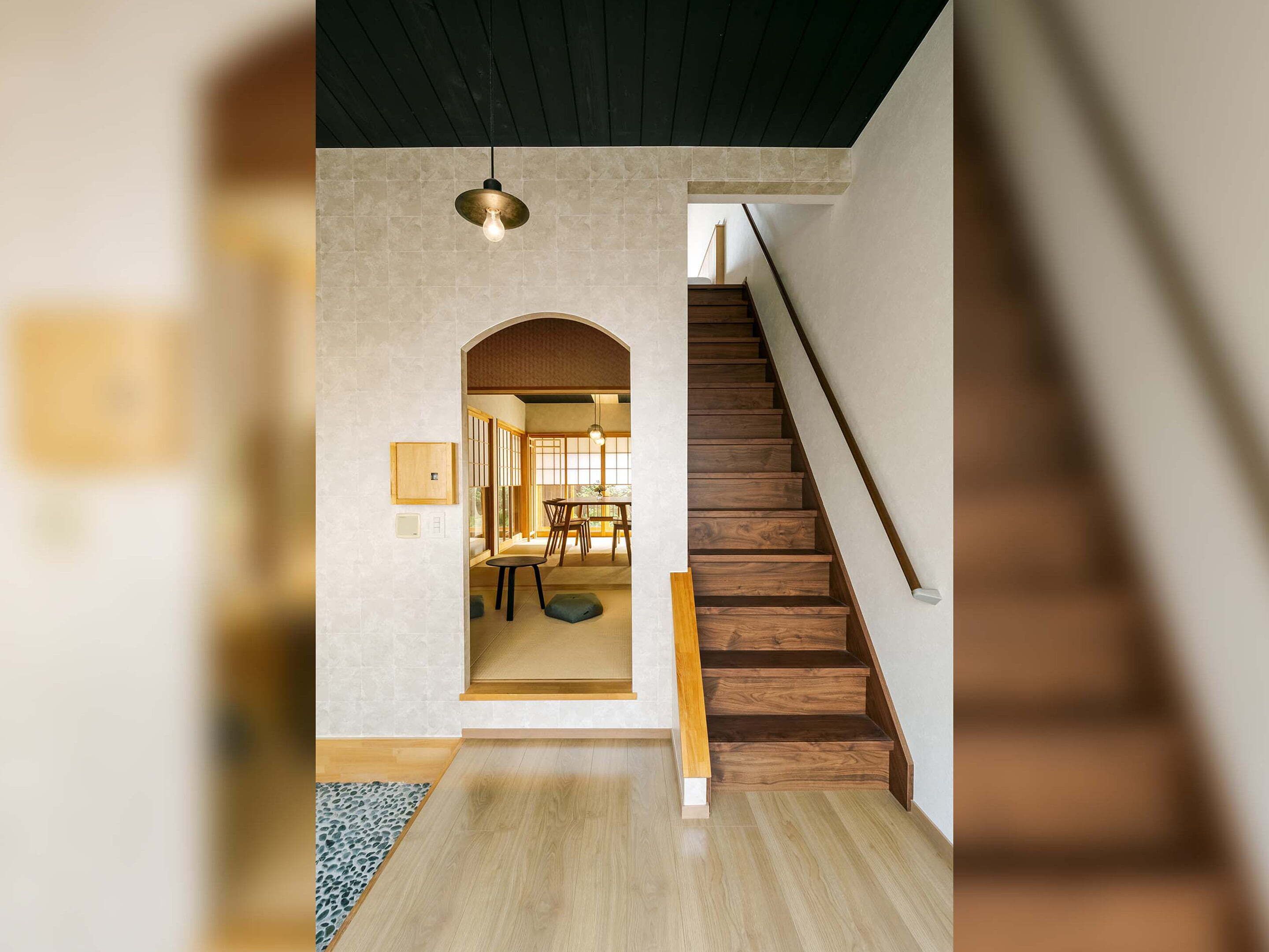 A staircase leading to a dining area with wooden flooring and a light fixture above.