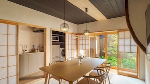 Una habitación tradicional japonesa con suelo de tatami, una mesa de madera y vistas a zonas verdes.