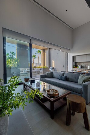 A modern living room with a sofa, coffee table, and a view of the outdoors.