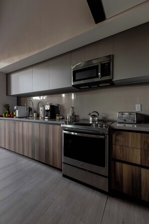 Eine moderne Küche mit Edelstahlgeräten, Holzschränken und einem eingebauten Backofen.