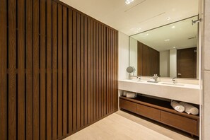 Un baño moderno con pared de paneles de madera, un espejo grande, un lavamanos blanco y un perchero para toallas.