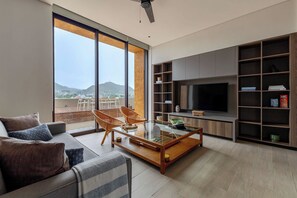 A modern living room with a sofa, chairs, a coffee table, a TV, and a bookshelf.