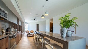 Une cuisine moderne avec un îlot central, des tabourets de bar, un ventilateur de plafond et une plante en pot.