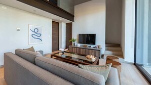 Un salon moderne comprenant un canapé, une table basse, un téléviseur et un escalier menant à un niveau supérieur.