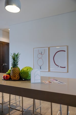 A bar area with a counter, a pineapple, a watermelon, and a sign with a drawing. - Capitalia | Oceanview Escape w/ Gym at the Marina (Cabo San Lucas)