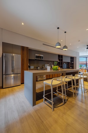 A modern kitchen with a central island, bar stools, and a dining area with a view.
