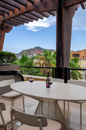 An outdoor patio with a round table, chairs, and a bottle of wine.