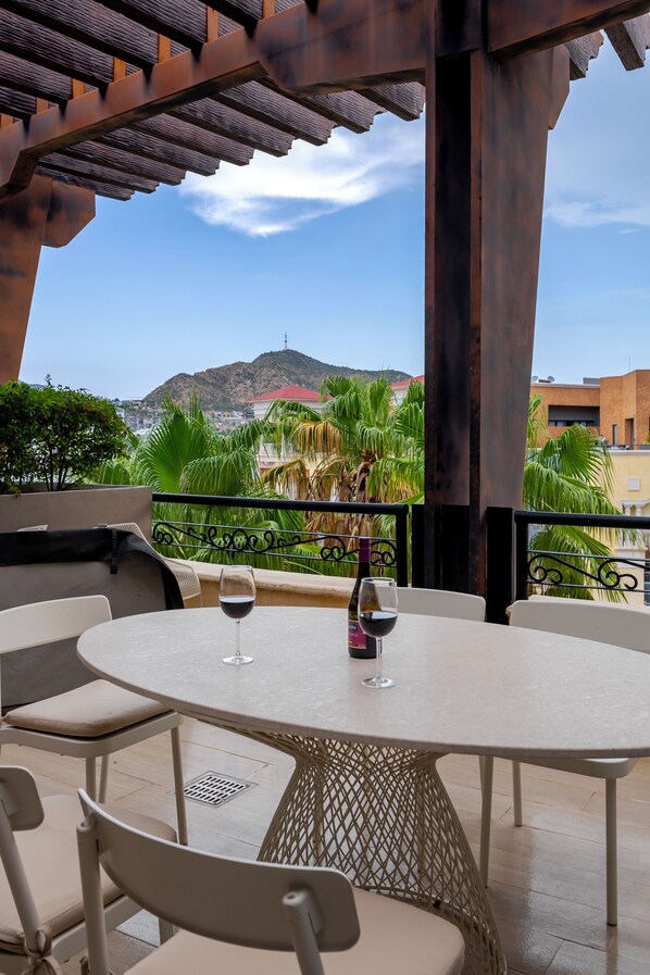 An outdoor patio with a round table, chairs, and a bottle of wine.