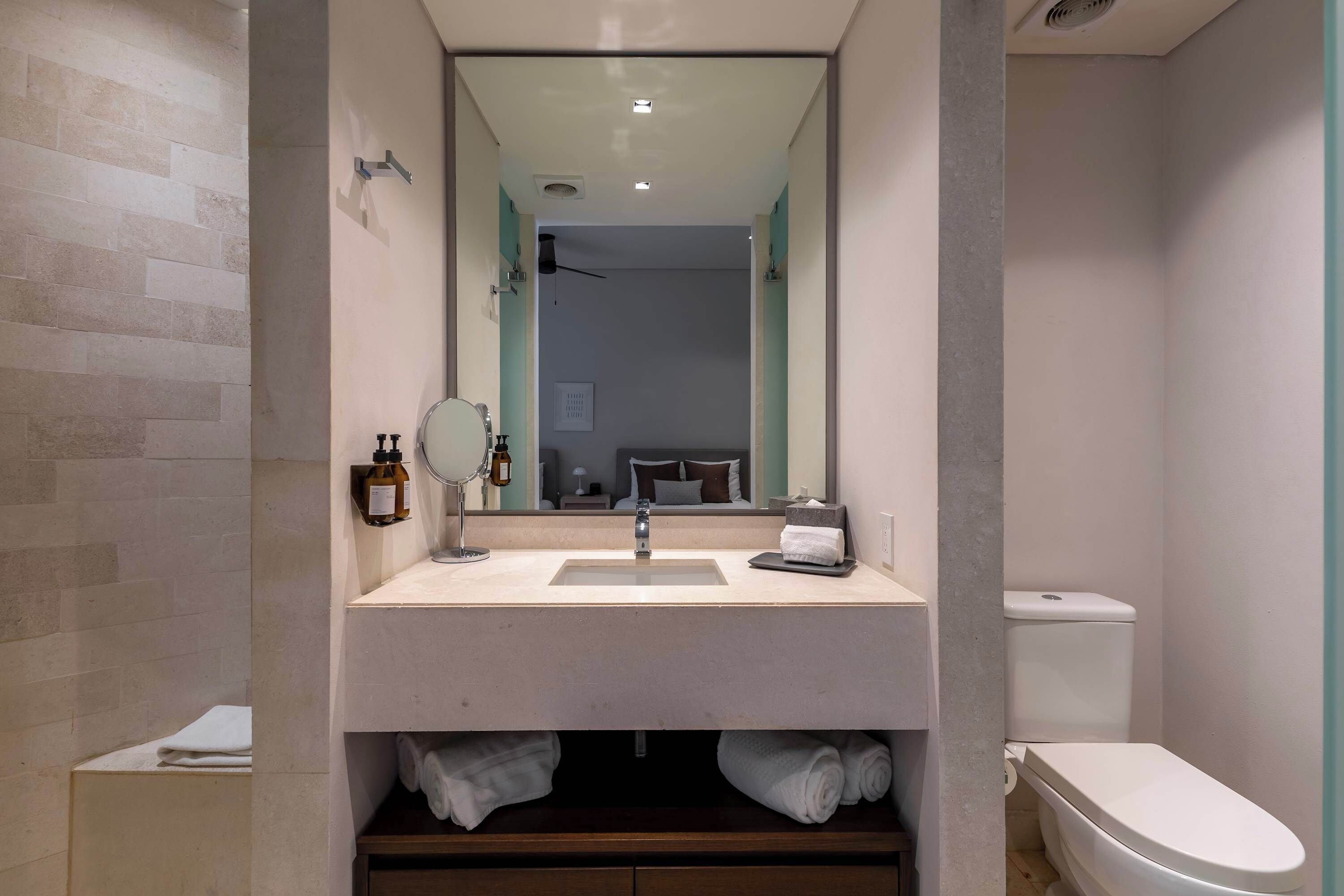 A modern bathroom with a sink, mirror, and toilet.
