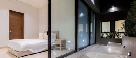 A modern bedroom with a bed, bedside table, and a view through a glass door.