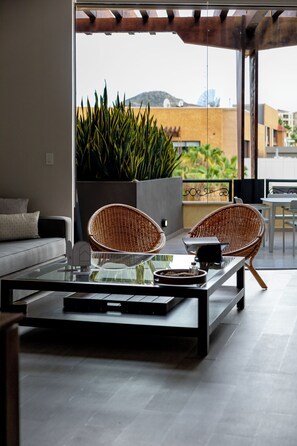 A modern outdoor seating area with a glass-top table, two wicker chairs, and a potted plant.