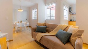 A modern living room with a beige sofa, a dining table with chairs, and a kitchen area with a sink and cabinets. - Capitalia | Chill Stay & Near Condesa & Museums (Ciudad de México)