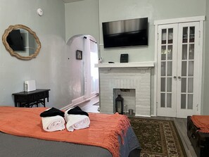 A hotel room with a bed, a television, a fireplace, and a mirror.