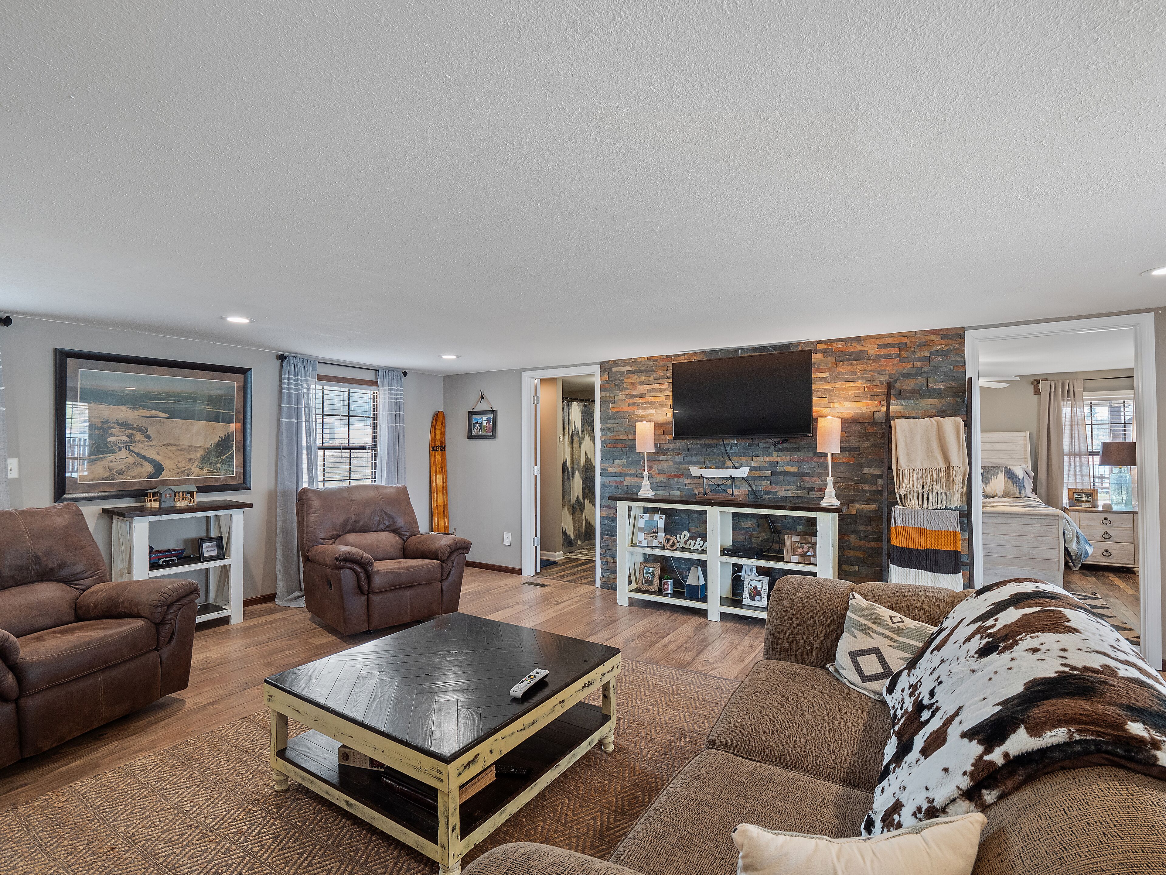 A living room with a fireplace, a mounted TV, and a large window with curtains.