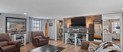 A living room with a fireplace, a mounted TV, and a large window with curtains.