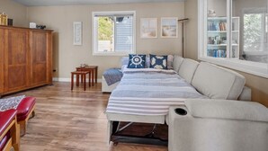 Een gezellige kamer met een bed, een houten kast, een tafeltje en een boekenplank.