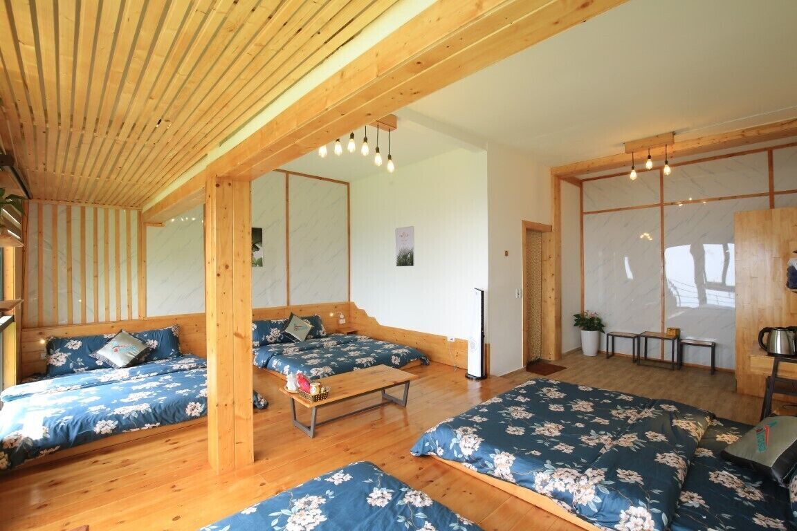 Ett rum med synliga träbjälkar, en bäddsoffa med blommigt tyg, ett litet bord och utsikt genom en skjutdörr.