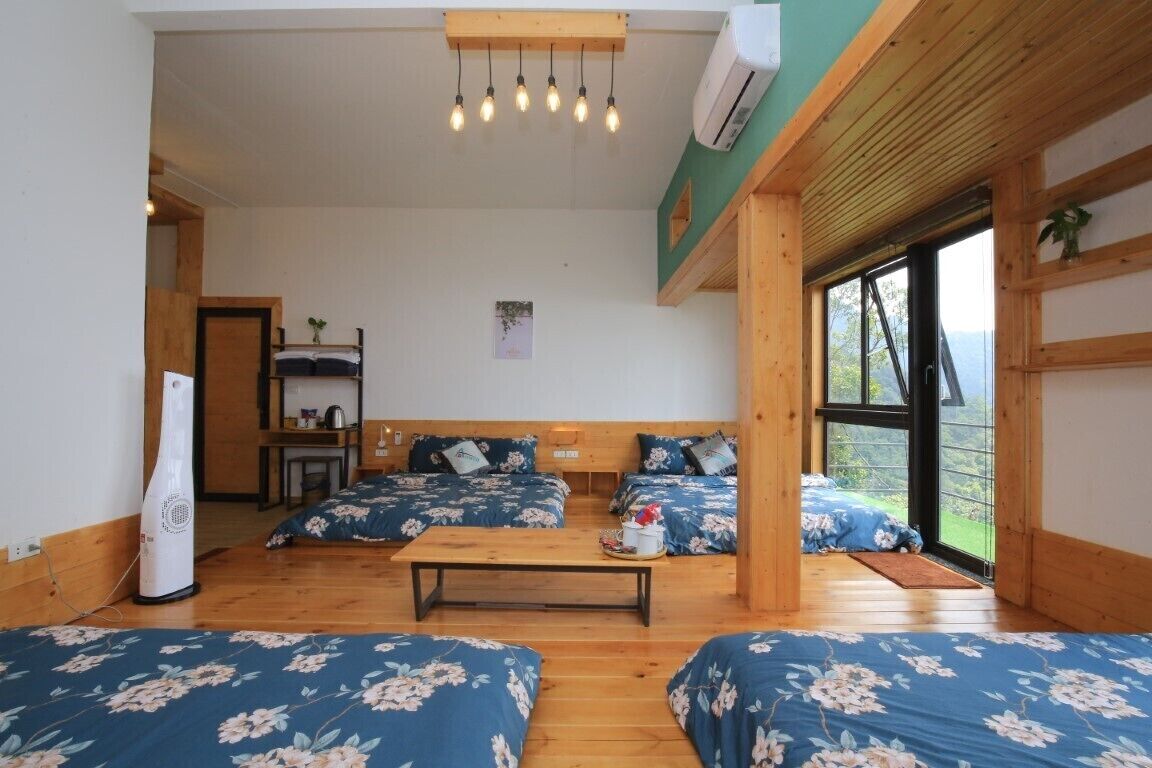 Een kamer met houten vloeren, een centrale tafel en vier bedden met bloemenbeddengoed.