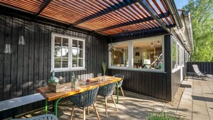 A wooden house with a covered patio, a dining table with chairs, and a window overlooking the interior. - "Fridtjof" - 550m to the fjord by Interhome (Hemmet)