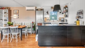 A modern kitchen with a central island, wooden flooring, and a dining area with white chairs. - "Fridtjof" - 550m to the fjord by Interhome (Hemmet)
